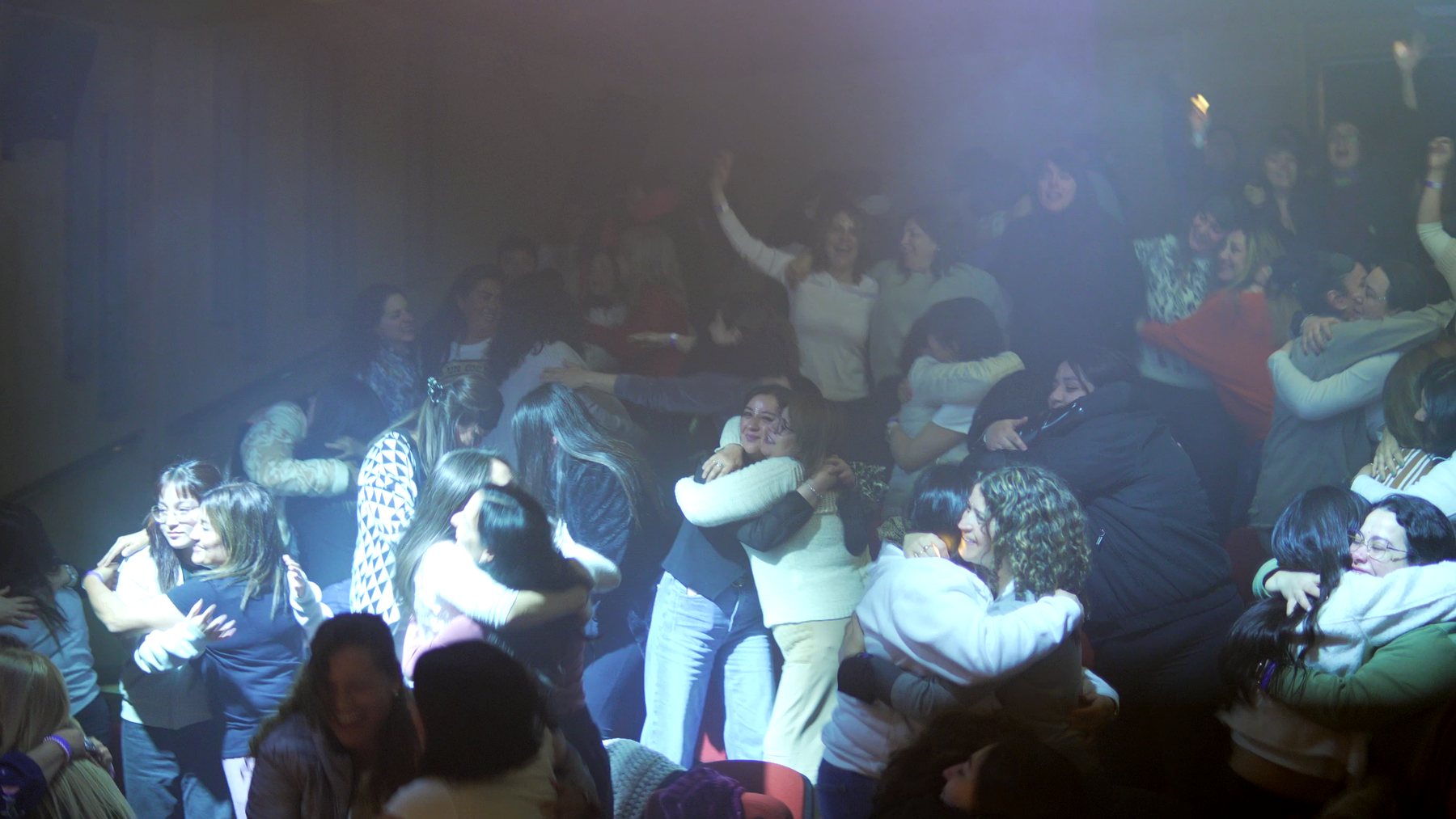 Participantes abrazándose en la sala